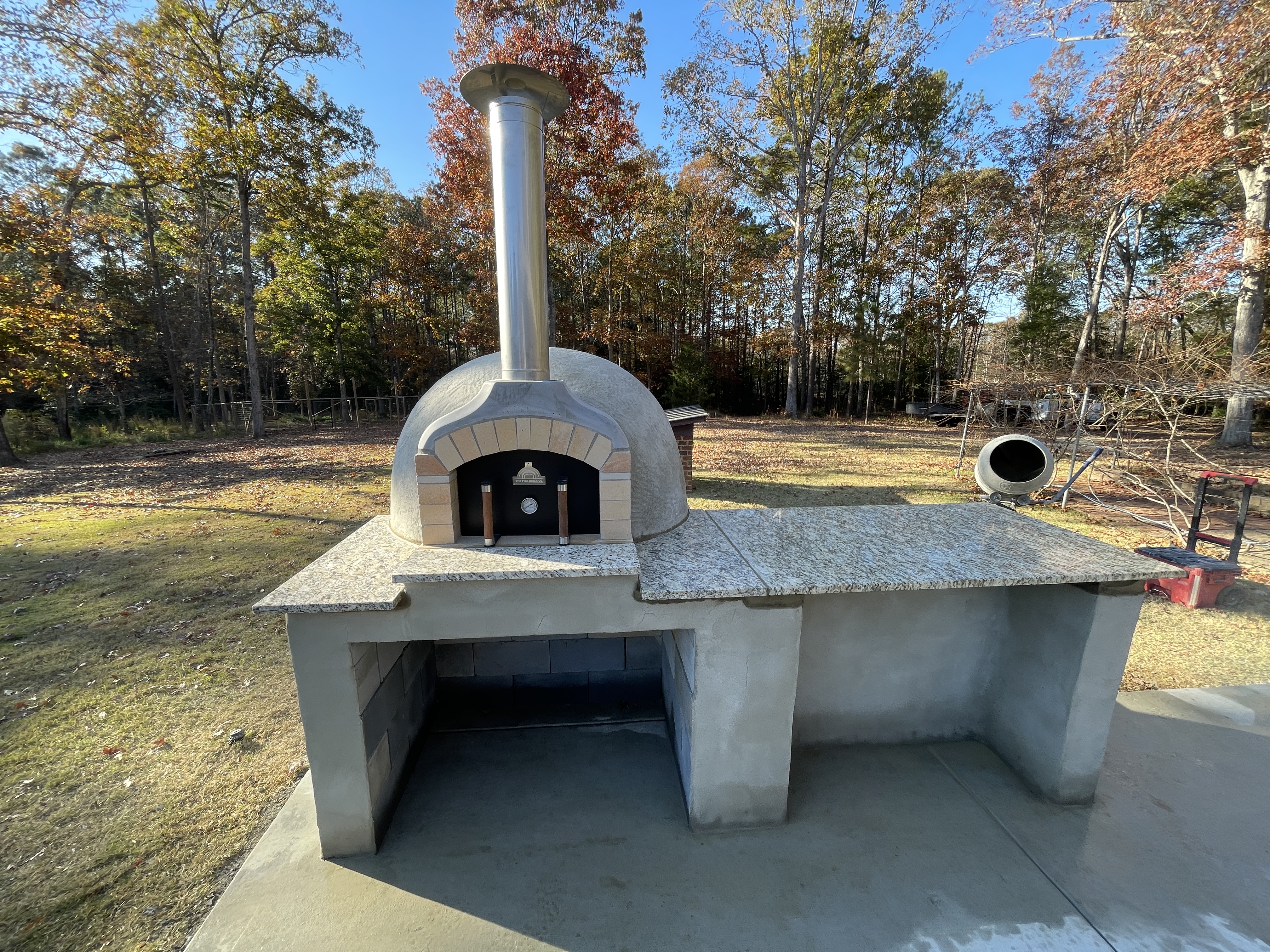 Completed custom outdoor pizza oven with granite countertop and stainless chimney
