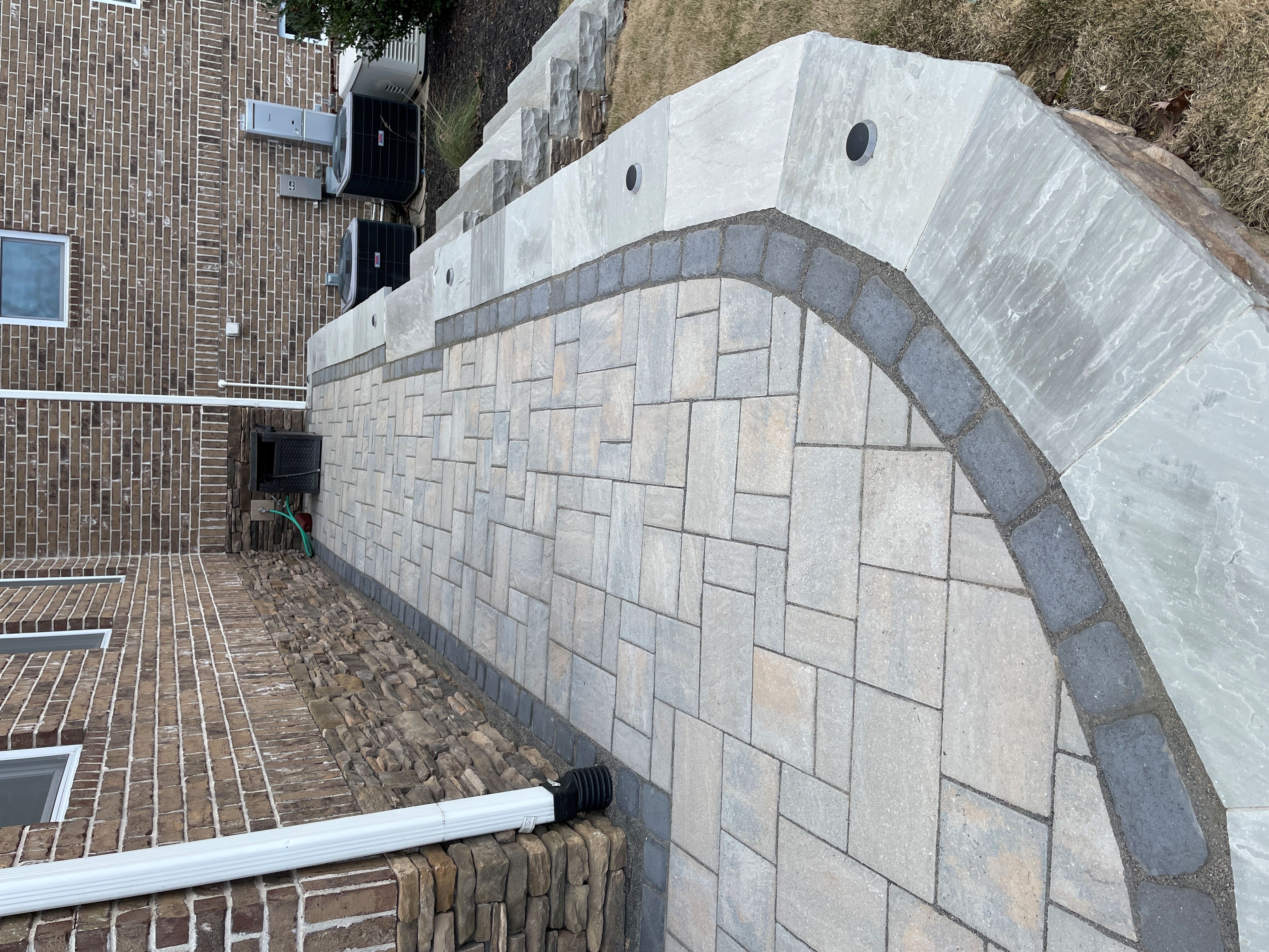 Large format stone paver patio with curved wall