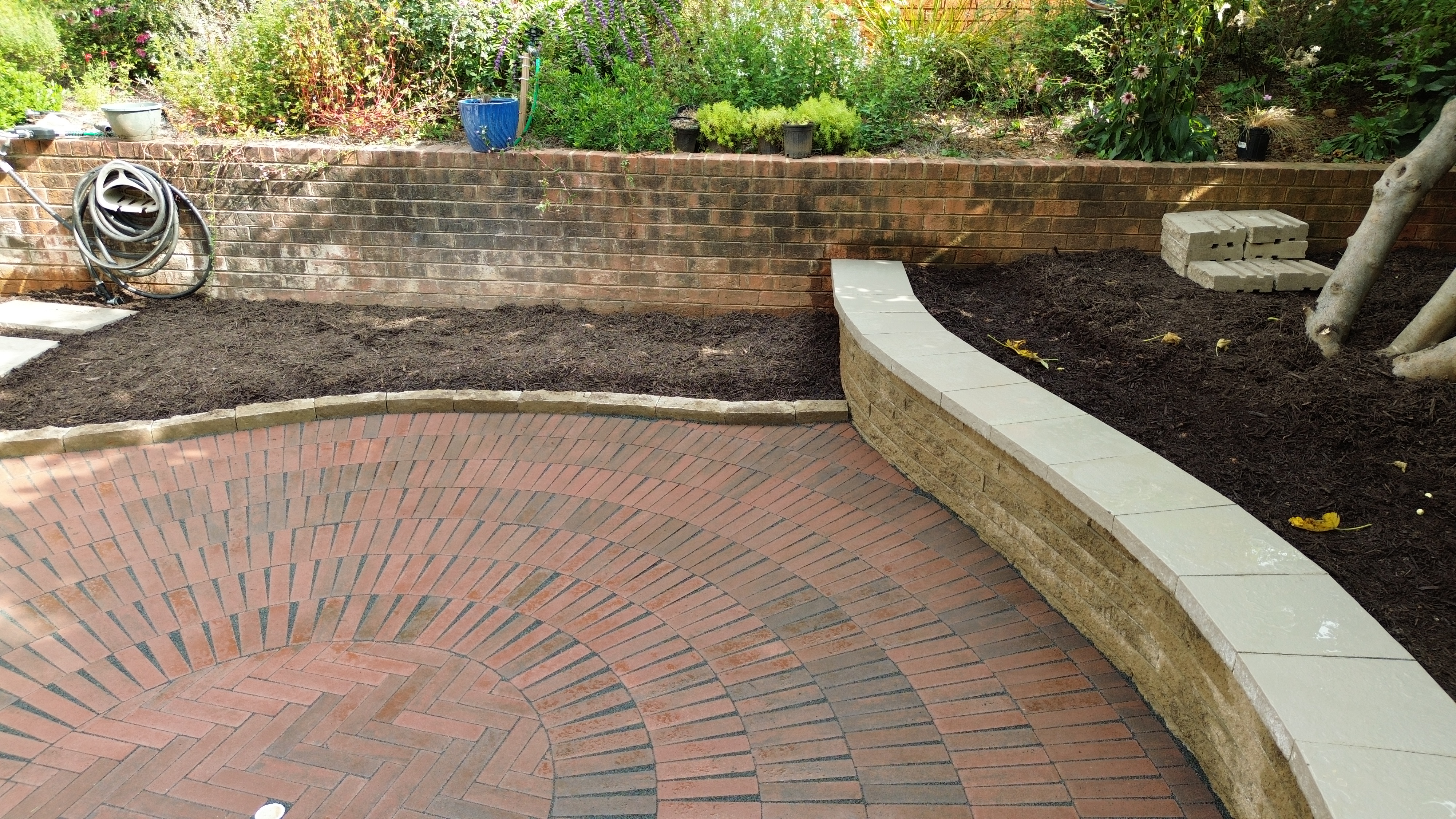 Circular brick patio with curved retaining wall and garden