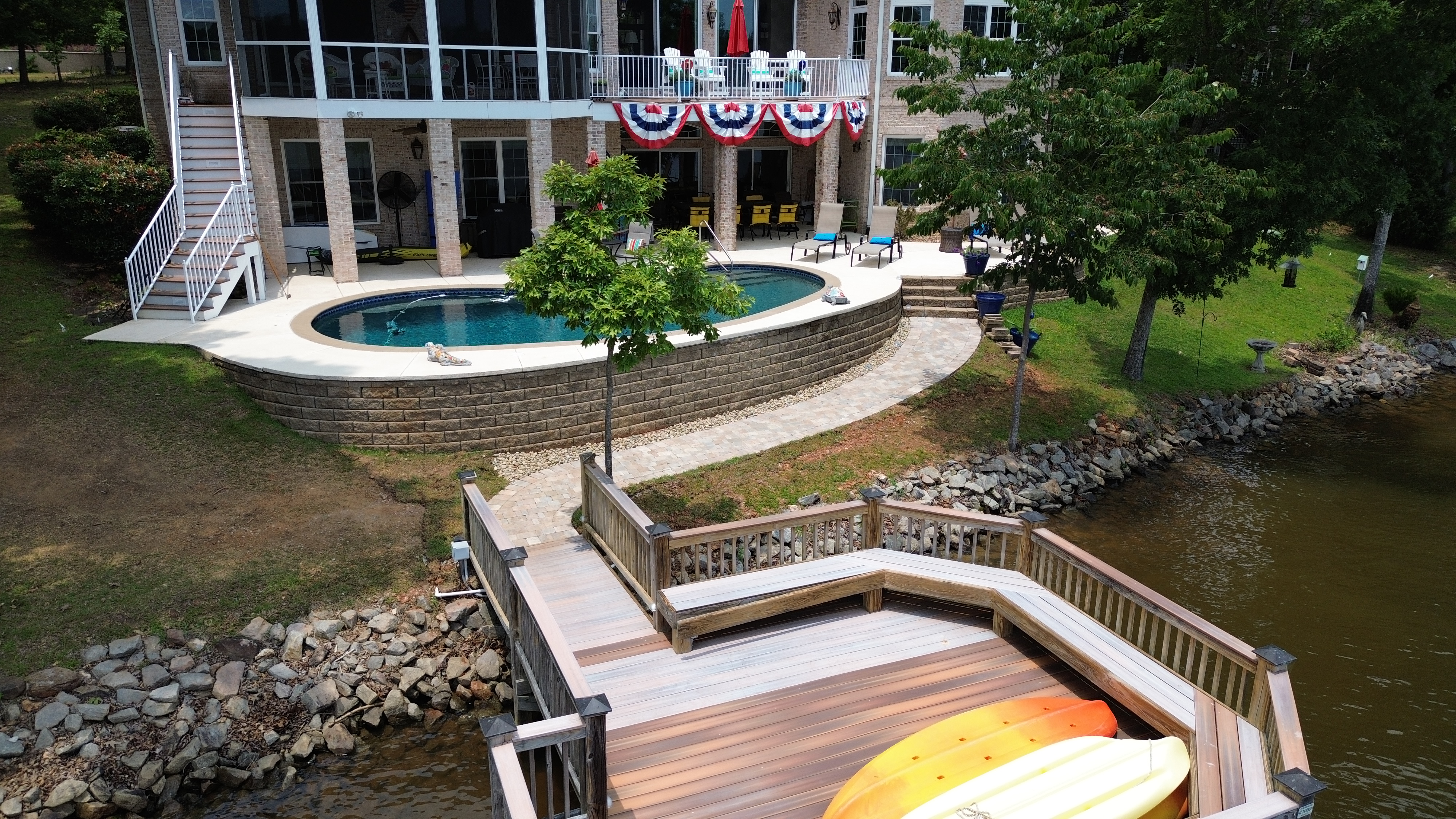 Aerial view of pool deck with retaining wall and paver path on lakefront property